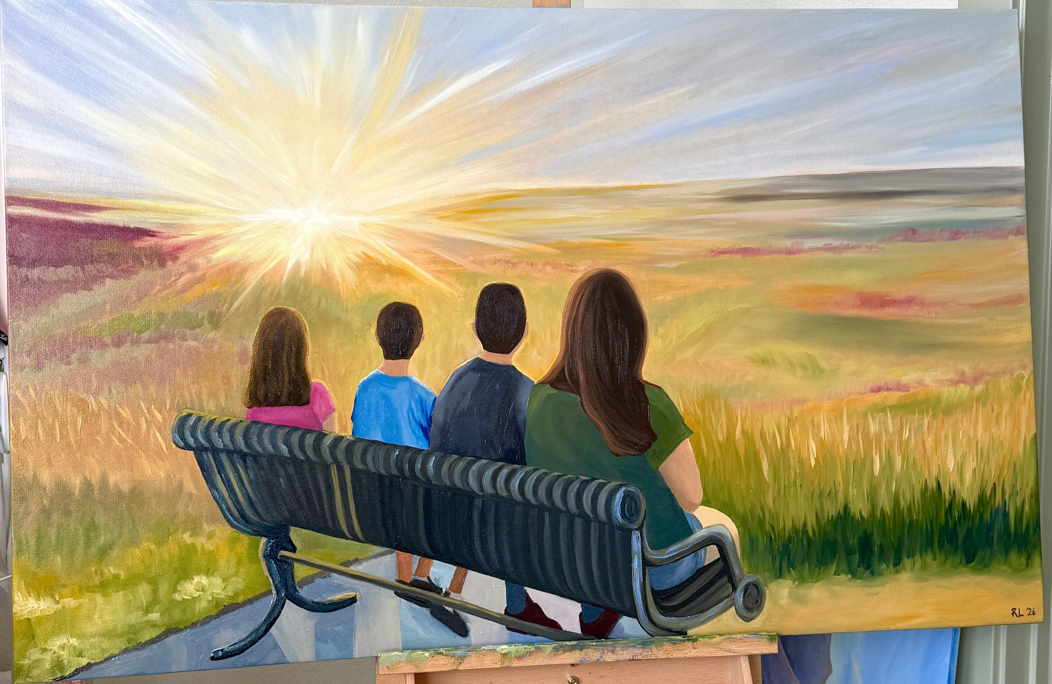 Painting of a family on a bench with a sunset scene, displayed on an easel.